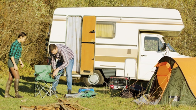 Piękna młoda para wysiada z retro kampera na dziko. Namiot kempingowy. Relaksujący weekend.