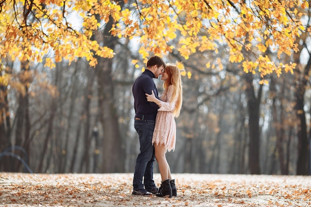 Piękna Młoda para zakochanych, uśmiechając się radośnie na tle żółtych liści na drzewach