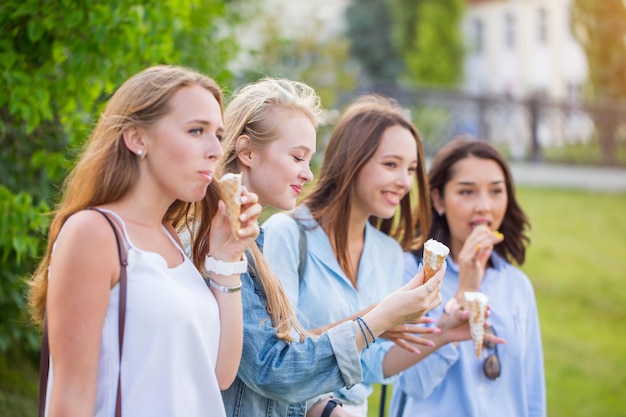 Piękna młoda studentka jedząca lody w parku na tle przyrody