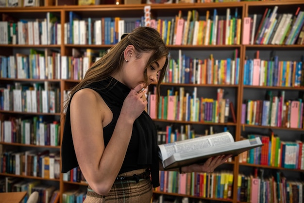 Piękna młoda studentka przyszła do biblioteki, aby się uczyć. Koncepcja biblioteki. Koncepcja czytania