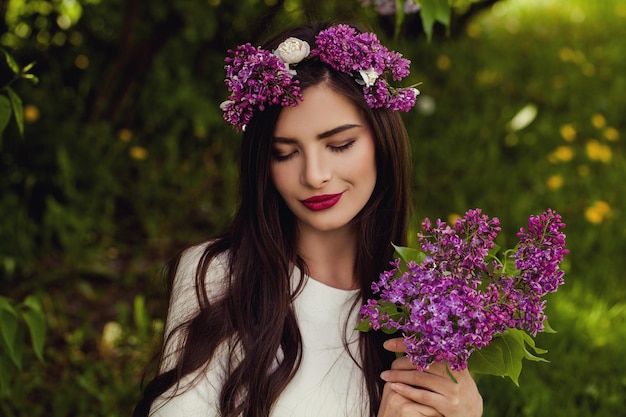 Piękna modelka dziewczyna z makijażem i zdrową fryzurą Młoda kobieta trzyma kwiaty bzu na zewnątrz