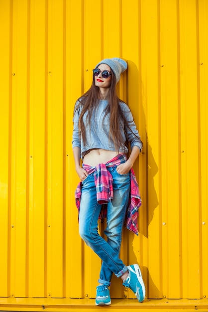 Piękna modna nastolatka na żółtej ścianie