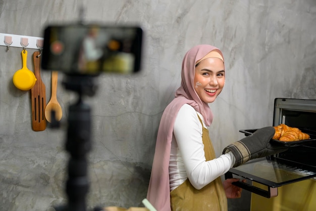 Piękna muzułmanka robi piekarnię podczas transmisji na żywo lub nagrywania wideo w mediach społecznościowych