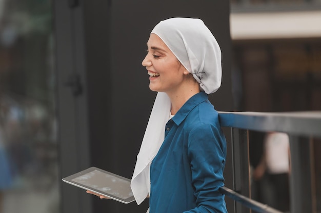 Piękna muzułmańska dziewczyna używa cyfrowego tabletu do komunikacji z przyjacielem na świeżym powietrzu