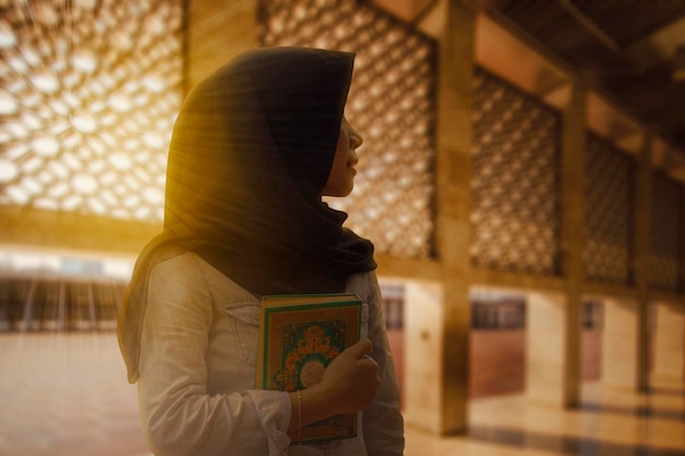 Piękna muzułmańska kobieta trzymająca Koran o zachodzie słońca