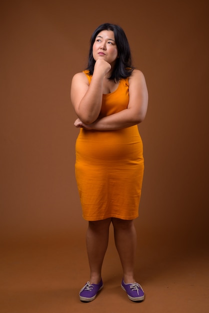 piękna nadwaga azjatycka kobieta ubrana w pomarańczową sukienkę bez rękawów