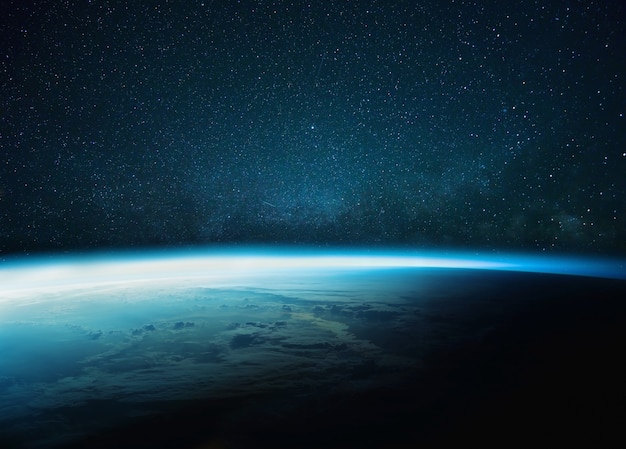 Zdjęcie piękna niebieska planeta ziemia z niebieską poświatą z gwiaździstą i mleczną drogą. wschód słońca w kosmosie