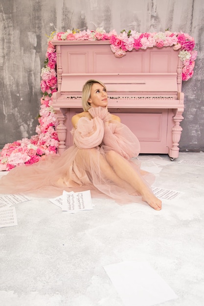 Piękna pani w różowej sukience i różowym fortepianie. Wysokiej jakości zdjęcie