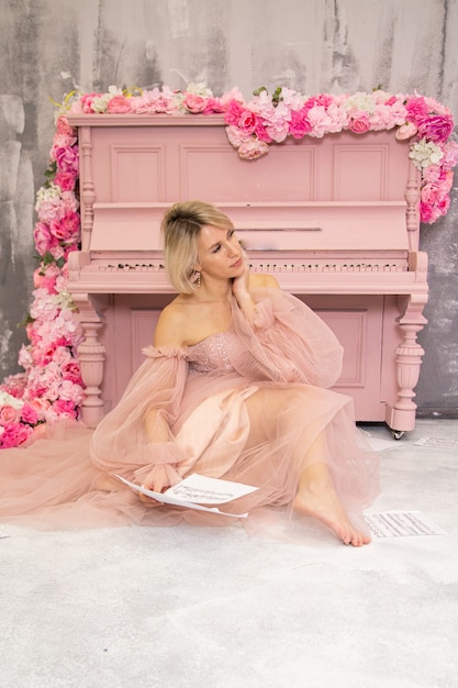 Piękna pani w różowej sukience i różowym fortepianie