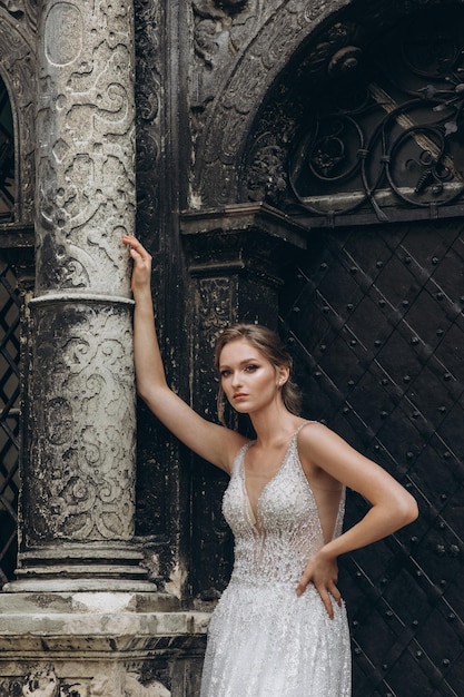 Piękna panna młoda w luksusowej sukni ślubnej stoi przed budynkiem