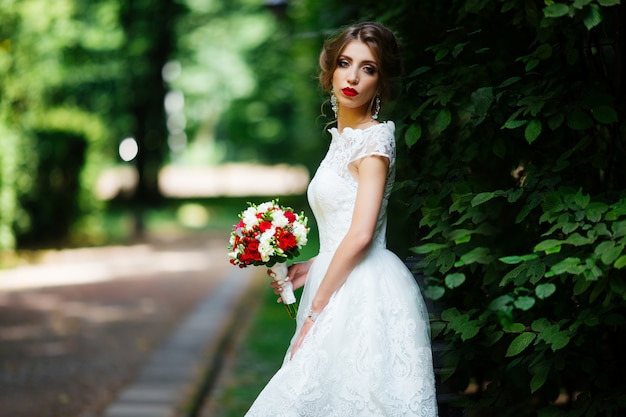 Piękna panna młoda z ślubnym bukietem w jej rękach outdoors w parku