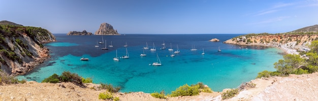 Piękna panorama zatoki Cala Hort z morskimi jachtami żaglowymi i górą Es Vedra. Ibiza, Baleary. Hiszpania