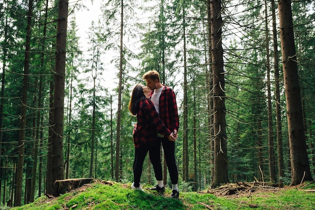 Piękna para mężczyzna i kobieta w czerwonych koszulach stoją w pięknym górskim lesie