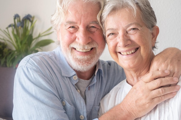 Piękna para seniorów rasy kaukaskiej przytulająca się, siedząca w domu na kanapie Spokojni starsi ludzie na emeryturze