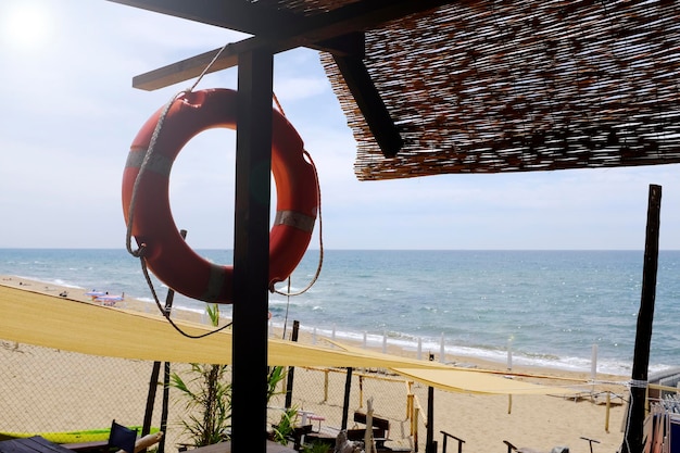 Piękna plaża z morzem na rozmytym tle z kołem ratunkowym i słomianym dachem na pierwszym planie