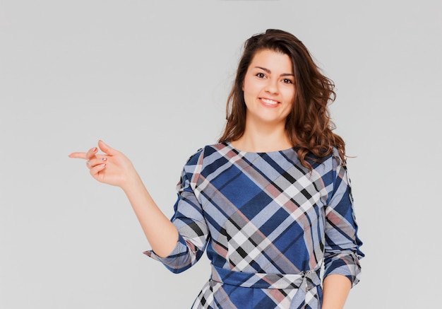 Piękna pozytywna uśmiechnięta brunetki dziewczyna w szkockiej kraty sukni pokazuje up