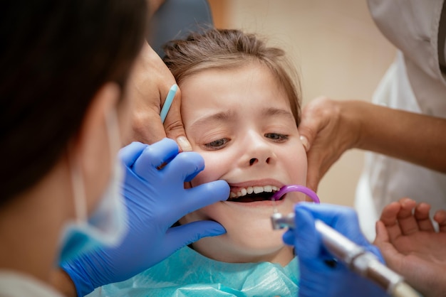 Piękna przestraszona dziewczynka na wizytę w gabinecie dentystycznym. Dentysta naprawia jej zęby. Prawdziwi ludzie.