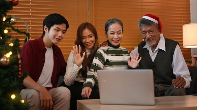 Piękna rodzina nawiązująca wideorozmowę na laptopie i wspólnie świętująca święta Bożego Narodzenia w domu Koncepcja świąt i uroczystości