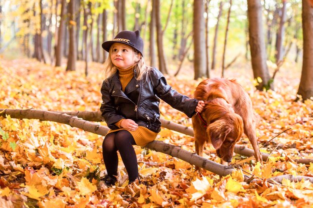 Piękna rodzina z psem golden retriever na spacerze w jesiennej słonecznej przyrodzie