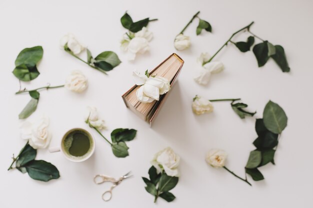 piękna romantyczna kompozycja z filiżanką zielonej herbaty matcha i kwiatami róży na białym tle