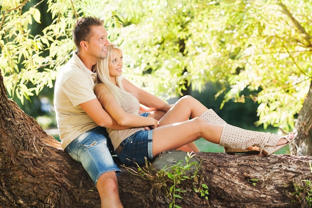 Piękna romantyczna para w objęciach w parku, siedząc na drzewie.