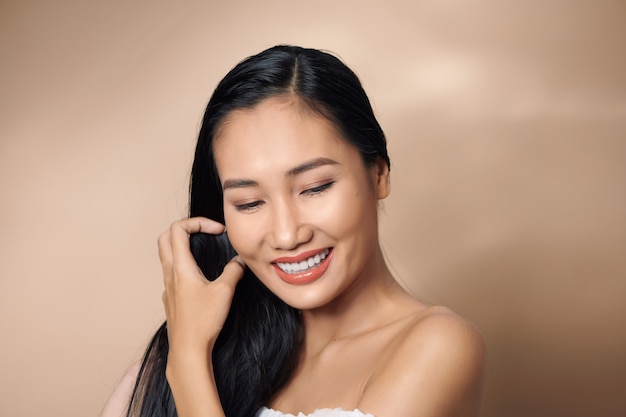 Piękna seksowna azjatycka kobieta modelka pozuje na beżowym tle
