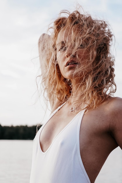 Piękna seksowna kobieta w białym stroju kąpielowym z odkrytymi plecami pozowanie w pobliżu jeziora, zdjęcie w stylu vintage