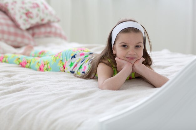 Piękna słodka ciemnowłosa dziewczyna w piżamie leży na łóżku