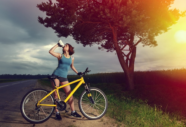 Piękna sport kobieta z rower wodą pitną z butelki.