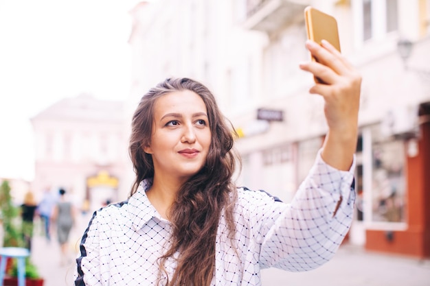Piękna stylowa kobieta robi selfie za pomocą smartfona w centrum miasta