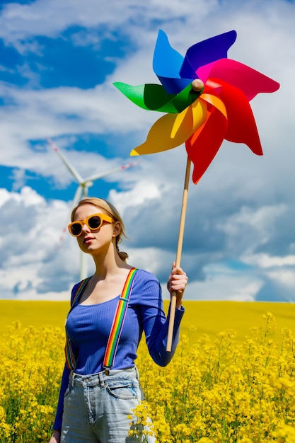 Zdjęcie piękna suczka w tęczowych szelkach lgbt do spodni i wiatraczka w polu rzepaku