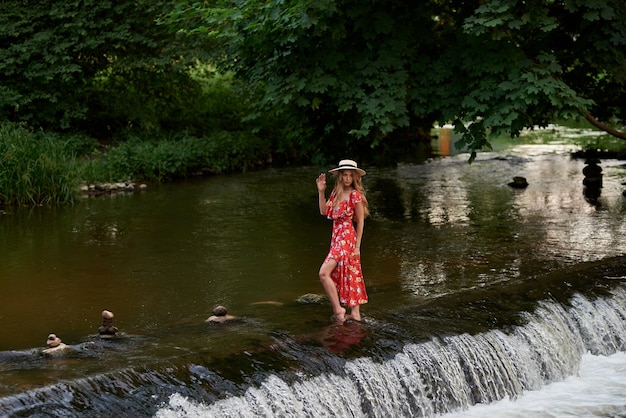 Piękna Szczęśliwa Blondynka W Letniej Sukience I Słomkowym Kapeluszu Stoi W Wodzie