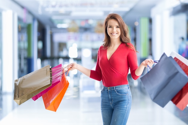 Piękna szczęśliwa dziewczyna z kartą kredytową i torbami na zakupy w centrum handlowym