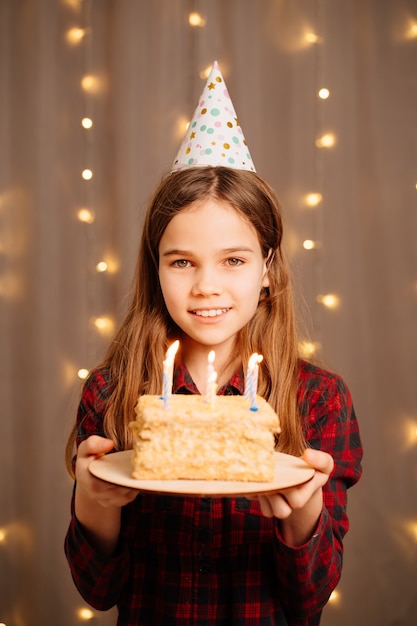 Piękna szczęśliwa dziewczyna z tortem urodzinowym. tradycją, aby złożyć życzenie i zgasić ogień na imprezie. Święto.