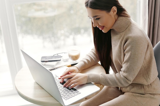 Piękna szczęśliwa kobieta pracująca z laptopem Uśmiechnięta biznesowa kobieta w biurze przy użyciu komputera