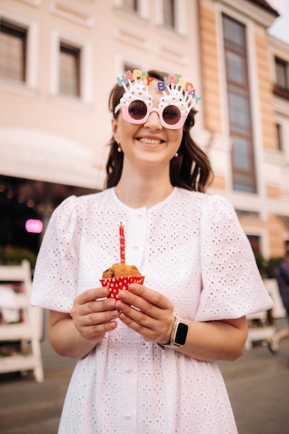 Piękna Szczęśliwa Kobieta W Białej Sukni Trzyma W Rękach Tort Na Ulicy Miasta świętującego Swoje Urodziny