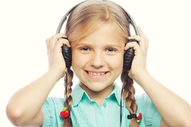 Zdjęcie piękna szczęśliwa mała dziewczynka ze słuchawkami.