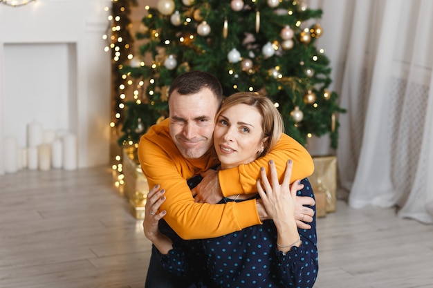 Piękna szczęśliwa para w świątecznej scenerii. Siedzenie i przytulanie przy choince w domu