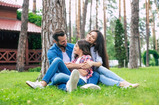 Piękna szczęśliwa rodzina siedząc razem na trawie i przytulanie