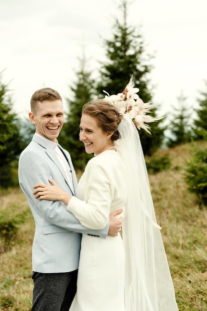 Piękna szczęśliwa uśmiechnięta młoda para zakochana przytulająca się w górach na tle pięknego krajobrazu moment dnia ślubu