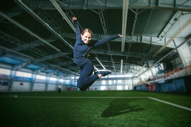 Piękna szczupła młoda kobieta w odzieży sportowej jest zaangażowana na stadionie sportowym