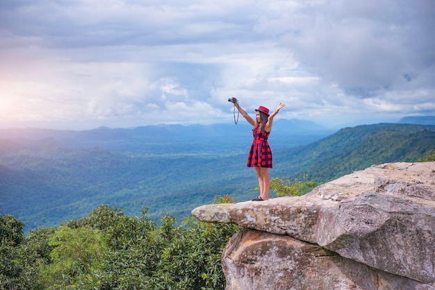 Zdjęcie piękna turystyczna dziewczyna stojąca na szczycie góry i robiąca zdjęcie doliny. klif sut phaendin, chaiyaphum, tajlandia