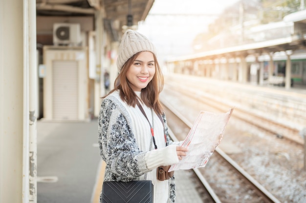 Piękna turystyczna kobieta stoi na Kolejowej platformie z jej mapą