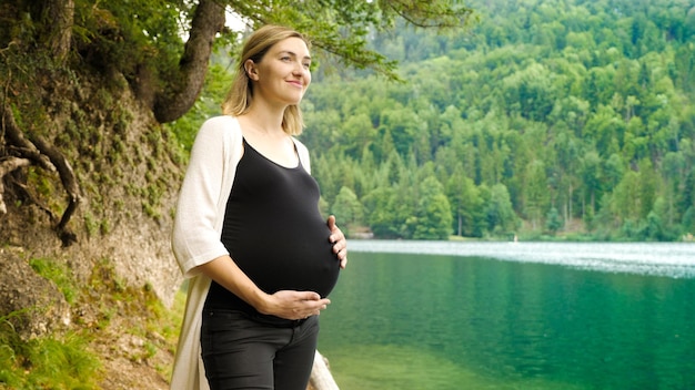 Piękna, urocza kobieta w ciąży w pobliżu górskiego jeziora w lesie.