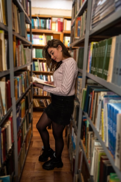 Piękna, urocza młoda dziewczyna czyta i studiuje w lokalnej bibliotece