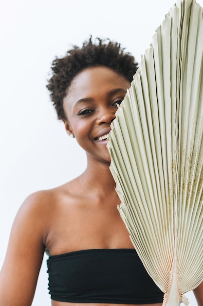 Piękna uśmiechnięta afro amerykańska młoda kobieta uroda modelka patrząca na kamerę z suchym liściem