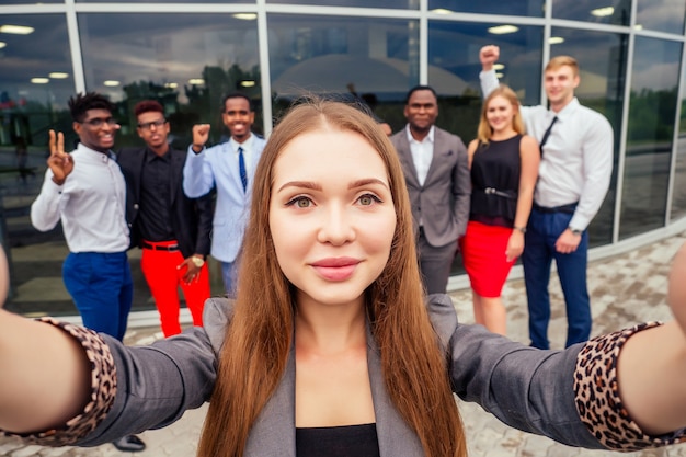 Zdjęcie piękna uśmiechnięta bizneswoman z afroamerykańskim i europejskim partnerem udanym wielorasowym zespołem mężczyzn biznesowych biorących selfie razem na aparacie