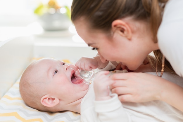 Piękna uśmiechnięta matka i jej dziecko bawić się w domu.