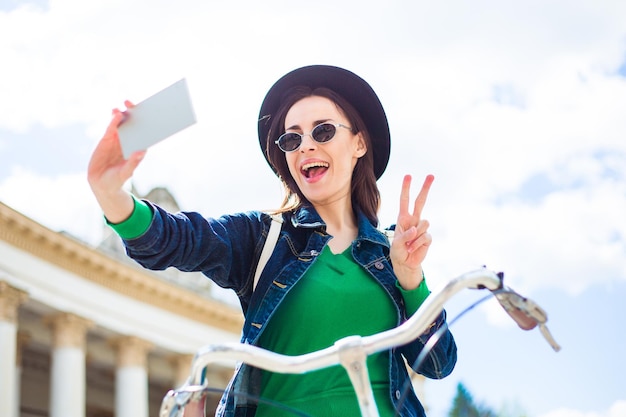 Piękna Uśmiechnięta Młoda Kobieta Na Rowerze Robi Selfie Przez Telefon I Uśmiecha Się