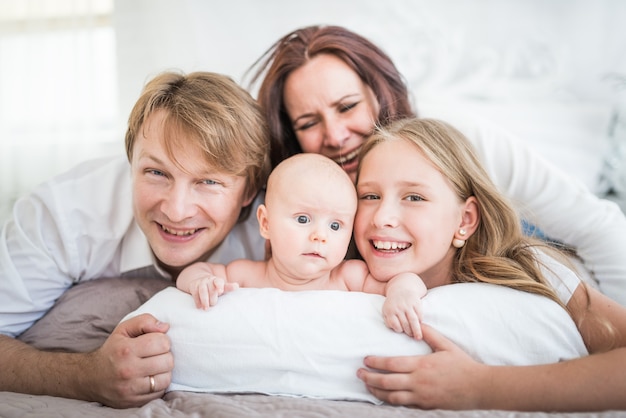 Piękna Uśmiechnięta Młoda Rodzina Mama Tata Starsza Córka I Noworodek Leżą Na Dużym łóżku W Jasnej Sypialni